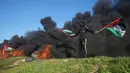 Seorang demonstran mengibarkan bendera nasional saat protes terhadap serangan militer Israel ke Kota Nablus, Tepi Barat, di sepanjang pagar perbatasan dengan Israel di sebelah timur Kota Gaza, 22 Februari 2023. Para pejabat Palestina mengatakan sejumlah warga Palestina telah terbunuh dan lebih dari seratus orang terluka dalam serangan tentara Israel yang jarang terjadi di Tepi Barat. (AP Photo/Adel Hana)