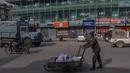 Seorang pria Kashmir mendorong kereta tangannya saat dia berjalan melewati area pasar tertutup selama penguncian akhir pekan di Srinagar, Kashmir yang dikuasai India, Sabtu (15/1/2022).  Pihak berwenang di bagian Kashmir India mengumumkan pembatasan penuh selama akhir pekan. (AP Photo/Dar Yasin)