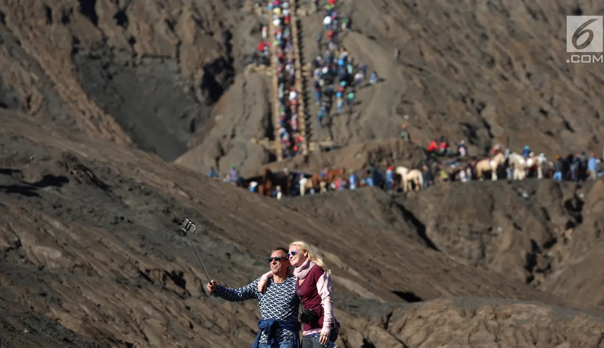 Wisatawan asing berswafoto di kawasan Gunung Bromo, Malang, Jawa Timur, (29/7). Ratusan wisatawan berbagai daerah setiap harinya memadati kawasan Bromo untuk berwisata melihat terbitnya matahari dan juga kawah Gunung Bromo. (Liputan6.com/Johan Tallo)