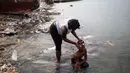 Seorang wanita memandikan putrinya di pantai saat mereka bersiap-siap untuk pergi ke gereja, di Warf of Port Cite Soleil di Port-au-Prince, Haiti (17/3). Cité Soleil merupakan lingkungan yang sangat miskin dan padat penduduk. (AP Photo/Dieu Nalio Chery)
