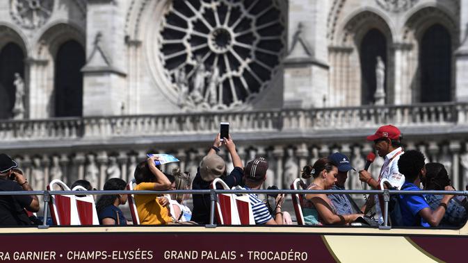 Wisatawan mengambil gambar Katedral Notre Dame yang sedang menjalani restorasi setelah rusak parah akibat kebakaran hebat, Paris, Prancis, Sabtu (13/7/2019). Katedral Notre Dame menjalani restorasi setelah mengalami kebakaran hebat pada 15 April 2019. (ALAIN JOCARD/AFP)