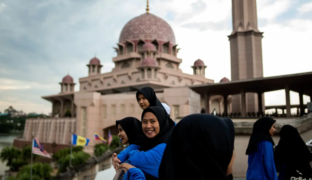 Gambar pada 22 November 2017, anak-anak sekolah berfoto dengan latar belakang masjid berwarna pink di kawasan Putrajaya, Malaysia. Karena keunikannya, masjid ini memiliki fungsi ganda sebagai rumah ibadah dan juga objek wisata. (MANAN VATSYAYANA/AFP)