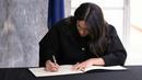Meghan Markle menandatangani buku belasungkawa bagi para korban serangan teror di Christchurch saat bersama sang suami, Pangeran Harry, mengunjungi New Zealand House di London, Selasa (19/3). (Ian Vogler/pool via AP)