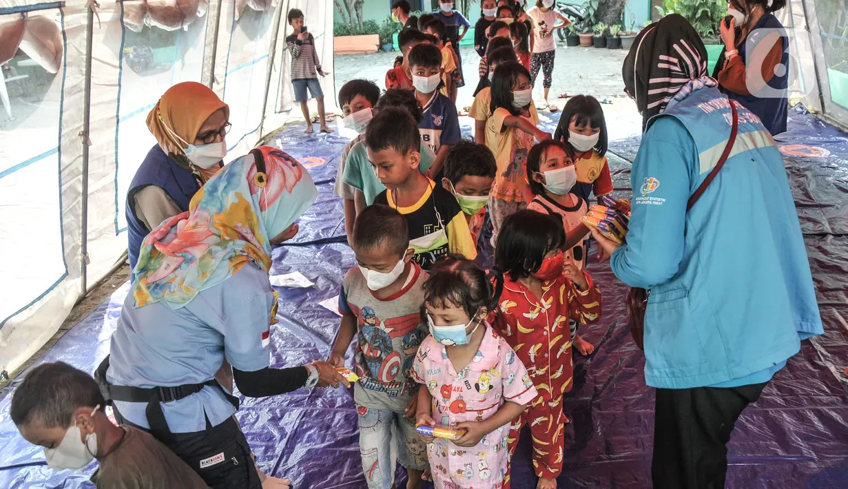 Anak-anak mendapatkan makanan usai mendengarkan dongeng di tenda pengungsian di SDN 09 Kebon Kosong, Kemayoran, Jakarta, Selasa (31/8/2021). Kegiatan bertujuan menghilangkan trauma atau rasa takut serta kebosanan anak-anak korban kebakaran saat berada di pengungsian. (merdeka.com/Iqbal S. Nugroho)