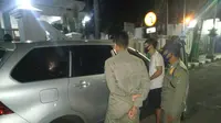 Satpol PP Tuban mengamankan sepasang anak muda dari dalam mobil untuk dimintai keterangan. Sebelumnya warga dibuat heboh dengan kejadian mobil bergoyang di depan rumah dinas Wakil Bupati Tuban. (Liputan6.com/ Ahmad Adirin)