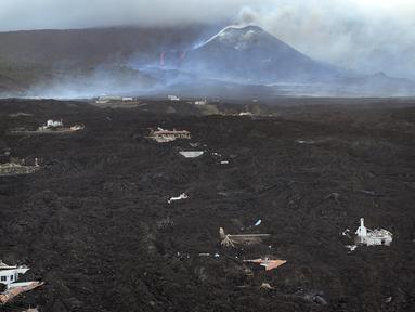 Aliran lahar menghancurkan rumah-rumah saat gunung berapi terus meletus di pulau Canary La Palma, Spanyol, Senin (29/11/2021). Beberapa ventilasi vulkanik baru dibuka di La Palma pada hari Minggu, melepaskan lava baru yang mengalir deras ke bawah. (AP/Emilio Morenatti)