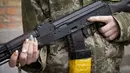 Seorang wanita pertahanan sipil bersenjata memegang senapan serbu Kalashnikov saat berpatroli di jalan yang kosong karena jam malam di Kiev, Ukraina, Minggu (27/2/2022). (AP Photo/Efrem Lukatsky)