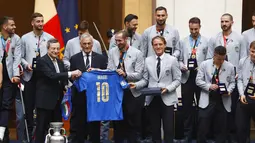 Perdana Menteri Italia Mario Draghi menerima jersey Italia dengan namanya dari Presiden Federasi Sepak Bola Italia Gabriele Gravina dan para pemain dan pelatih Roberto Mancini dalam sebuah upacara perayaan juara Euro 2020 di Istana Chigi di Roma, Senin (12/7/2021). (AP Photo/Riccardo De Luca)