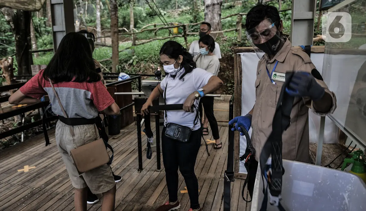 Petugas saat membantu pengunjung mengenakan tali pengaman sebelum melintasi Jembatan Gantung Situ Gunung, Sukabumi, Jawa Barat, Minggu (20/9/2020).  (merdeka.com/Iqbal S. Nugroho)