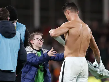 Penyerang Portugal Cristiano Ronaldo memberikan jerseynya untuk seorang fans cilik Irlandia yang berjalan ke lapangan pada akhir laga Grup A Kualifikasi Piala Dunia 2022 Zona Eropa di Stadion Aviva, Jumat (12/11/2021) dinihari WIB. Portugal ditahan imbang Irlandia 0-0. (AP /Peter Morrison)