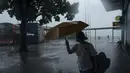 Seorang wanita memegang payung di bawah angin kencang di dekat kawasan pejalan kaki Victoria Habour saat badai tropis Ma-on melewati Hong Kong, Kamis (25/8/2022). Badai Tropis Ma-on semakin kuat saat menuju Hong Kong dan bagian tenggara lainnya China pada hari Rabu setelah menggusur ribuan orang di Filipina. (AP Photo/Anthony Kwan)