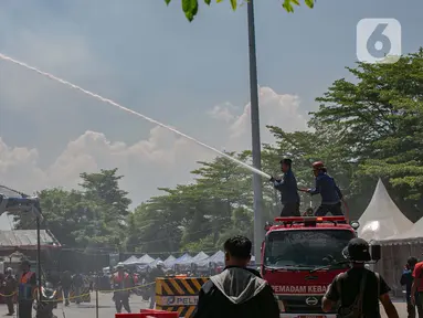 Petugas pemadam kebakaran melakukan penyiraman air ke tenda para pemudik motor di Pelabuhan Ciwandan, Banten, Minggu (7/4/2024). (Liputan6.com/Angga Yuniar)