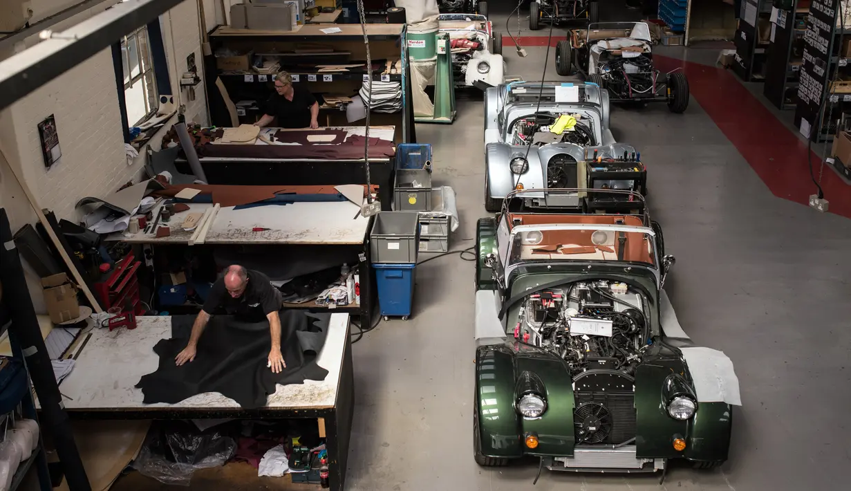 Pekerja mencetak kulit yang akan dibuat sebagai jok mobil klasik sport di pabrik mobil Morgan Motor Company di Malvern, Birmingham, Inggris (13/8/2019). Morgan Motor Company didirikan pada tahun 1909 oleh HFS Morga. (AFP Photo/Oli Scarff)