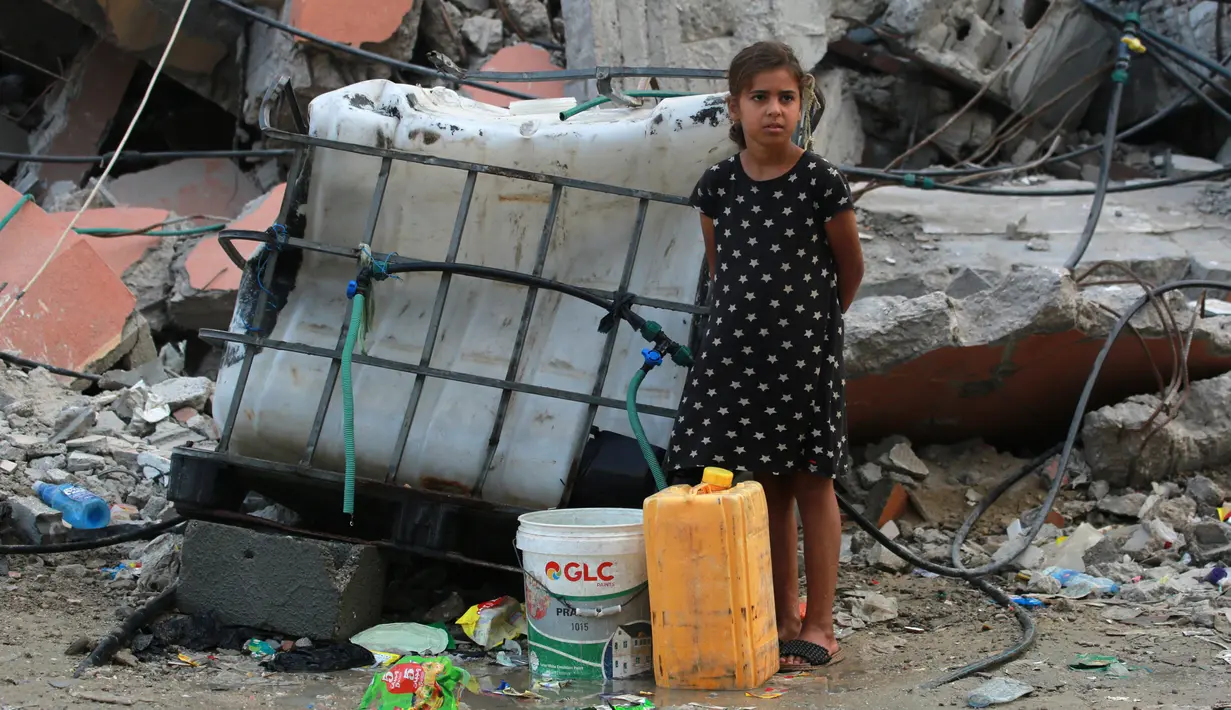 Seorang anak perempuan Palestina bersiap mengisi wadah plastik dengan air di titik distribusi di Khan Yunis di Jalur Gaza selatan pada 17 Oktober 2024. (BASHAR TALEB/AFP)