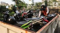 Petugas gabungan yang terdiri dari Satpol PP dan Dinas Perhubungan (Dishub) DKI Jakarta menata motor yang terjaring razia parkir liar di lokasi Citayam Fashion Week, kawasan Stasiun Dukuh Atas, Sudirman, Selasa (26/7/2022). Dishub DKI Jakarta mengamankan sebanyak 16 sepeda motor yang terpakir secara liar. (Liputan6.com/Faizal Fanani)