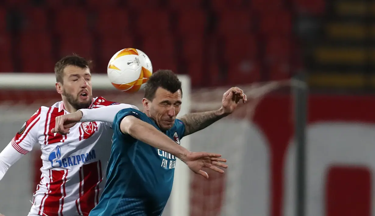 Penyerang AC Milan, Mario Mandzukic berebut bola dengan pemain Red Star Belgrade, Nemanja Milunovic pada leg pertama babak 32 besar Liga Europa di Rajko Mitic Stadium, Serbia (19/2/2021). Hasil imbang 2-2 menjadi keuntungan Milan yang akan menjadi tuan rumah di leg kedua. (AP Photo/Darko Vojinovic)