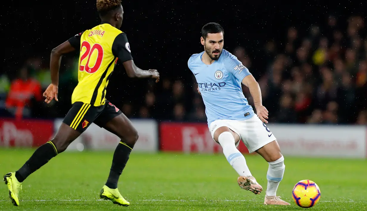 Gelandang Manchester City, Ilkay Gundogan berusaha mengumpan bola dari kawalan pemain Watford, Domingos Quina selama pertandingan lanjutan Liga Inggris di stadion Vicarage Road (4/12). City menang tipis atas Watford 2-1. (AP Photo/Frank Augstein)