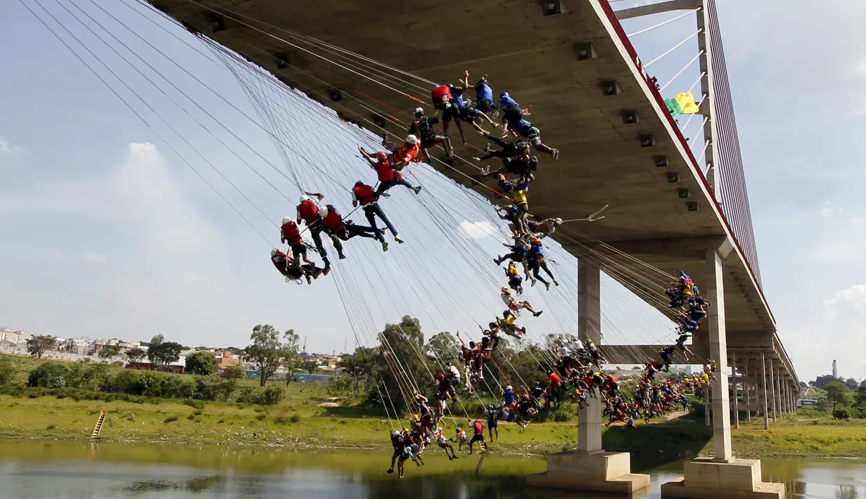 Ratusan orang menggunakan seutas tali melompat dari jembatan berketinggian 30 meter di Hortolandia, Brasil, Minggu (10/4). Sebanyak 149 orang mencoba membuat rekor dunia dengan melompat bersama dari atas jembatan. (REUTERS/Paulo Whitaker)