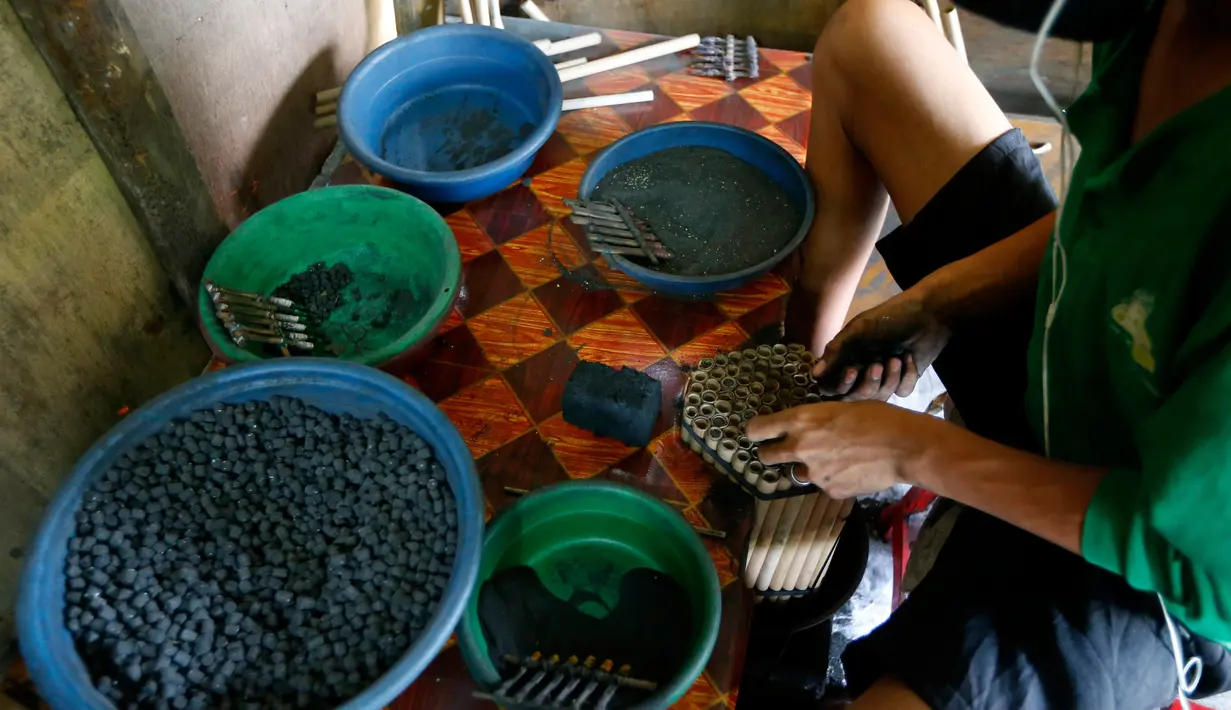 Pekerja memasukkan bubuk mesiu ke dalam sebuah tabung kecil saat membuat kembang api di sebuah gubuk, provinsi Bulacan, utara Manila, Rabu (27/12). Warga Filipina menyiapkan kembang api untuk menyambut tahun baru 2018. (AP/Bullit Marquez)