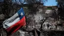Bendera Chili berkibar ketika warga membersihkan lahan dan rumah mereka yang terbakar di Villa Independencia, wilayah Valparaiso, Chili pada tanggal 5 Februari 2024. (Javier TORRES/AFP)