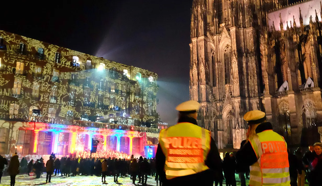 Petugas keamanan berjaga di depan gedung Katedral Cologne yang dihiasi instalasi cahaya, Jerman (31/12). Mereka punya caranya masing-masing untuk merayakan tahun baru, di Jerman mereka menikmati kilauan cahaya. (AFP/Patrik Stollarz)
