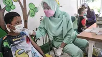 Petugas puskesmas menenangkan seorang anak sebelum disuntik vaksin DT di RPTRA Citra Permata, Jakarta, Selasa (28/9/2021). Kegiatan rutin tahunan tersebut bertujuan memberikan kekebalan tubuh pada anak sekolah terhadap penyakit DT dengan kuota 150 anak per hari. (merdeka.com/Iqbal S Nugroho)