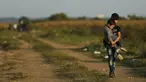 Seorang imigran remaja menggendong adiknya melintasi perbatasan dari Serbia ke Kroasia di Tovarnik (18/9/2015). (REUTERS / Antonio Bronic)