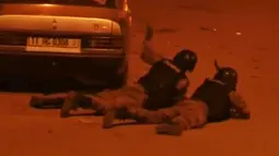 Petugas keamanan saat bersembunyi dibalik sebuah mobil saat terjadi penyanderaan yang dilakukan suatu kelompok radikal di Splendid, Ouagadougou, Burkina Faso, Jumat (15/1). (REUTERS / Reuters TV)