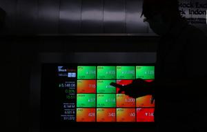 Pekerja melintas di dekat layar digital pergerakan saham di Gedung BEI, Jakarta, Rabu (14/10/2020). Pada pembukaan perdagangan pukul 09.00 WIB, IHSG masih naik, namun tak lama kemudian, IHSG melemah 2,3 poin atau 0,05 persen ke level 5.130, 18. (Liputan6.com/Angga Yuniar)