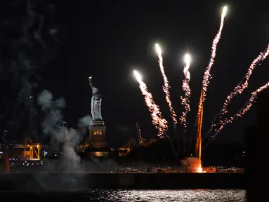 Kembang api yang diluncurkan dari tongkang meledak di atas Pelabuhan New York dan Patung Liberty di New York, Selasa (15/6/2021). Kembang api yang menandai berakhirnya pembatasan COVID-19 di seluruh negara bagian tersebut untuk menghormati para kelompok pekerja penting. (AP Photo/Craig Ruttle)