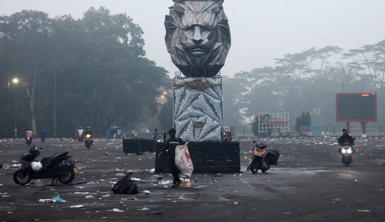Pengendara sepeda motor melintas di luar Stadion Kanjuruhan pada pagi hari setelah tragedi kerusuhan pada pertandingan sepak bola antara Arema dan Persebaya di Malang, Jawa Timur, Minggu (2/10/2022). Ratusan nyawa melayang pada kerusuhan usai Persebaya mengalahkan Arema tersebut. (PUTRI/AFP)