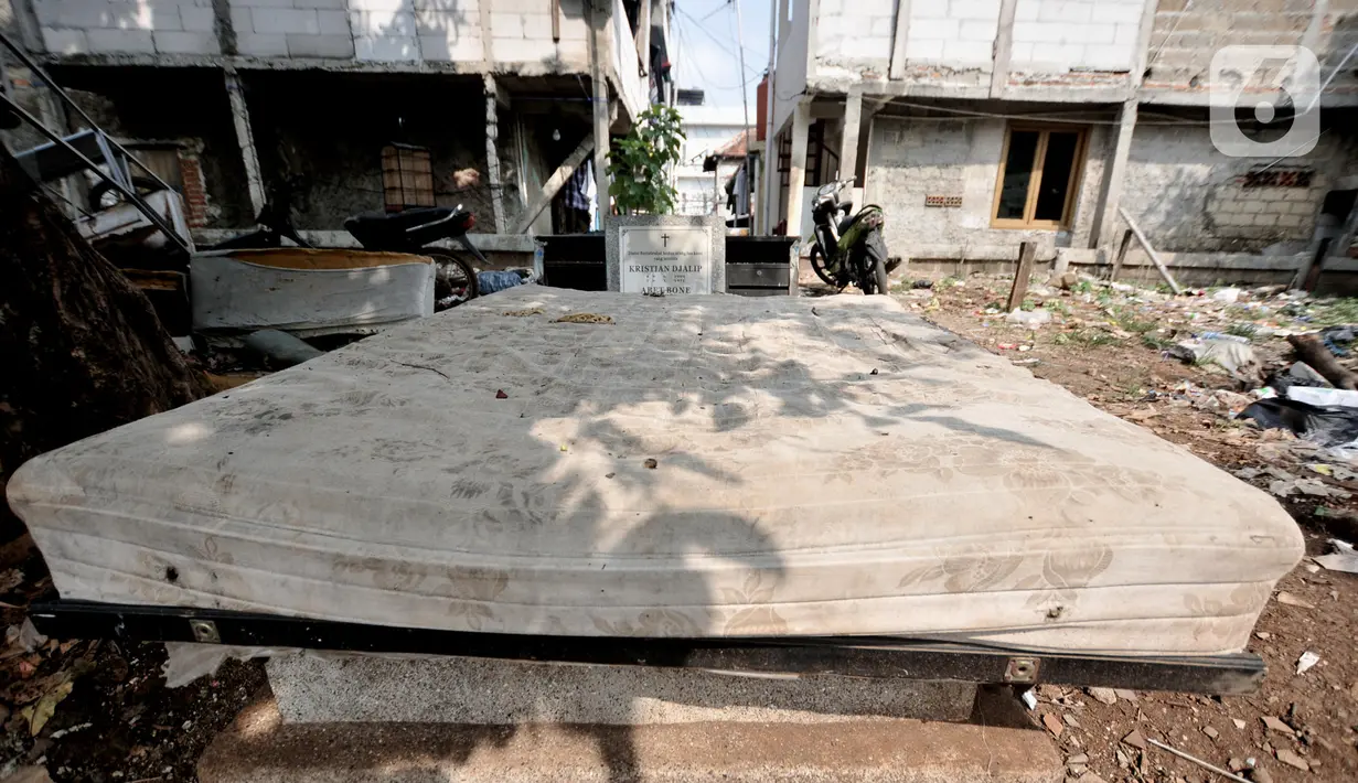 Sebuah makam tertutup kasur usang di TPU Menteng Pulo 2, Jakarta, Senin (9/12/2019). Minimnya kesadaran warga setempat ditambah tidak adanya fasilitas TPA dan perawatan  pengelola TPU menyebabkan kondisi kompleks makam sangat memprihatinkan akibat dipenuhi sampah. (merdeka.com/Iqbal S. Nugroho)
