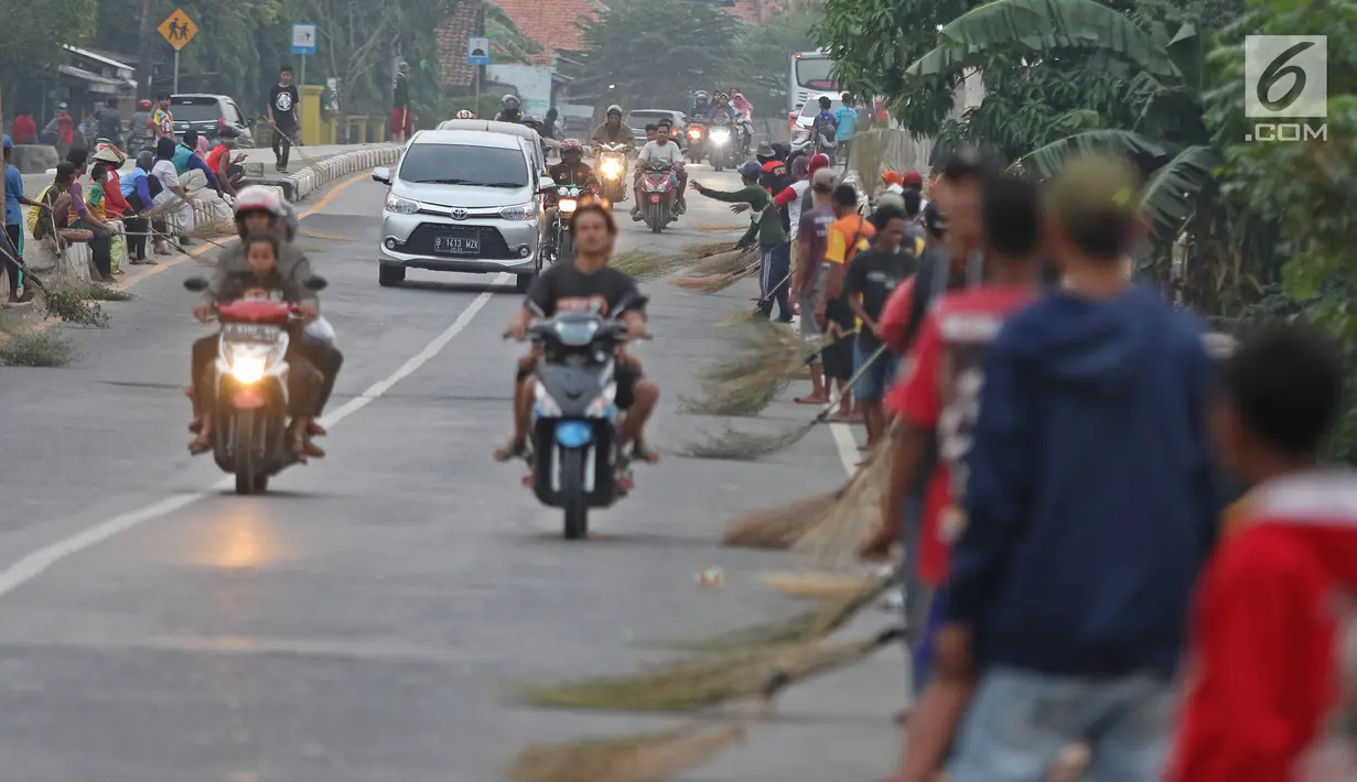 Warga membawa sapu menunggu pengguna jalan memberi sedekah dengan melempar uang di Jembatan Sewo, Jalur Pantura Sukra Indramayu, Jawa Barat, Senin (3/6/2019). Kehadiran pencari sedekah tersebut biasanya kian bertambah banyak saat menjelang arus mudik Lebaran. (Liputan6.com/Herman Zakharia)