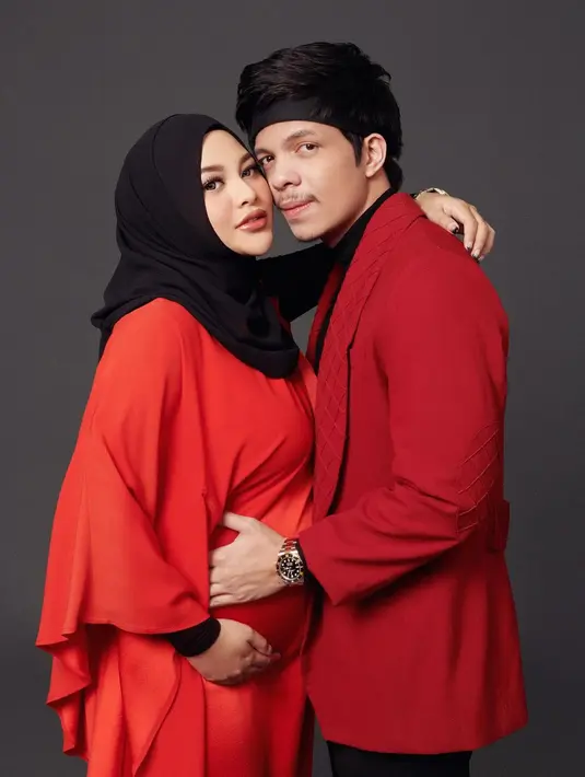 Kali ini dengan outfit bernuansa merah, Aurel tampil mengenakan long dress berwarna oranye kemerahan, dipadu hijab hitam polos. Sedangkan Atta terlihat mengenakan innerwear hitam yang dilayer dengan jas merah. Foto: Instagram.