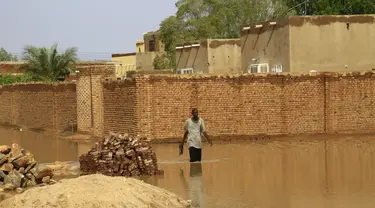 Seorang pria menyusuri jalanan yang tergenang banjir di Khartoum, Sudan (3/8/2020). Sudan dilanda banjir baru-baru ini akibat hujan lebat. (Xinhua/Mohamed Khidir)