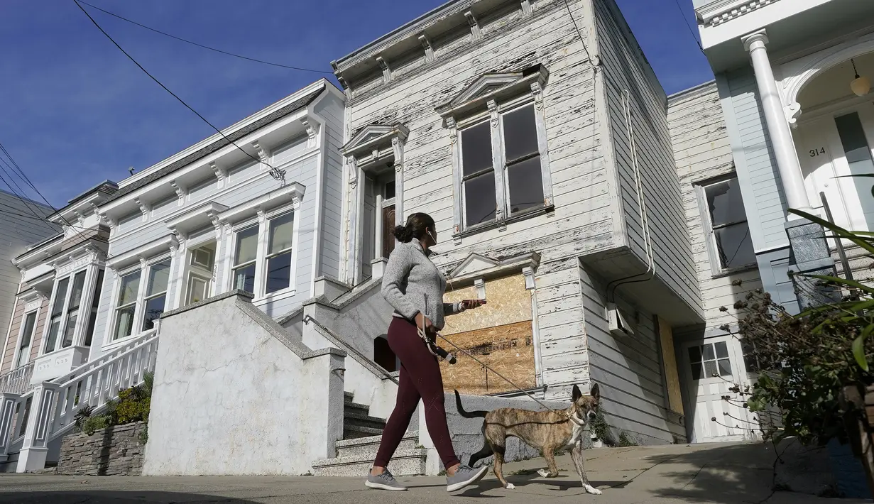 Pejalan kaki melewati rumah bergaya Victoria yang baru saja dijual di San Francisco, pada 14 Januari 2022. Rumah berusia 122 tahun yang sudah lapuk ini dipasarkan sebagai "rumah terburuk di blok terbaik" San Francisco terjual hampir 2 juta dollar AS atau sekitar Rp 28,6 miliar. (AP Photo/Jeff Chiu)
