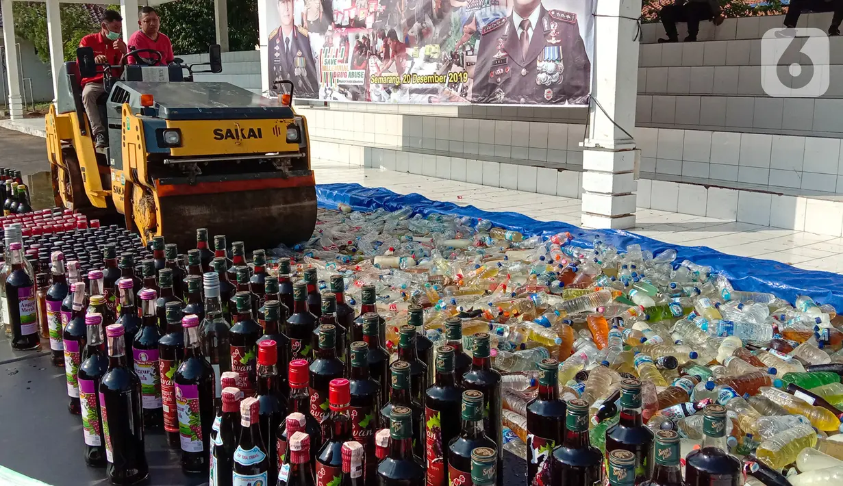 Petugas dengan alat berat menghancurkan botol minuman keras (miras) saat pemusnahan Miras dan barang bukti narkotika di Mapolrestabes Semarang, Jumat (20/12/2019). Pemusnahan barang bukti narkoba berupa sabu, inex dan pil koplo serta 5450 botol dan 140 liter ciu. (Liputan6.com/Gholib)