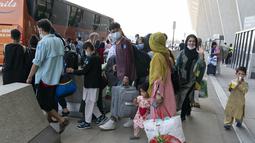 Keluarga dievakuasi dari Kabul, Afghanistan, menunggu untuk naik bus setelah mereka tiba di Bandara Internasional Washington Dulles, di Chantilly, Va, Rabu (25/8/2021). (AP Photo/Jose Luis Magana)