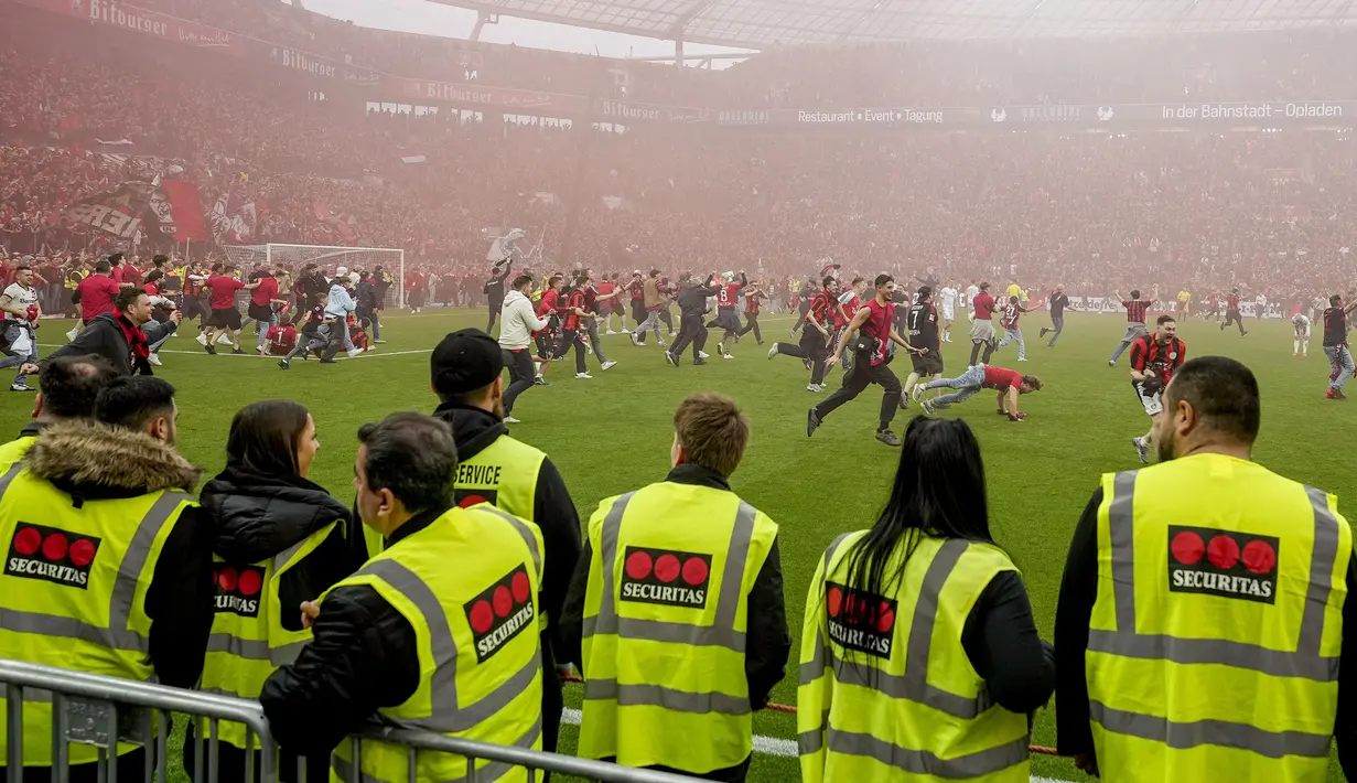Petugas keamanan tak mampu membendung para suporter yang memasuki lapangan untuk merayakan kemenangan Bayer Leverkusen saat memastikan gelar juara Liga Jerman 2023/2024 setelah mengalahkan Werder Bremen di BayArena, Leverkusen, Jerman, Senin (15/04/2024) WIB. (AP Photo/Martin Meissner)