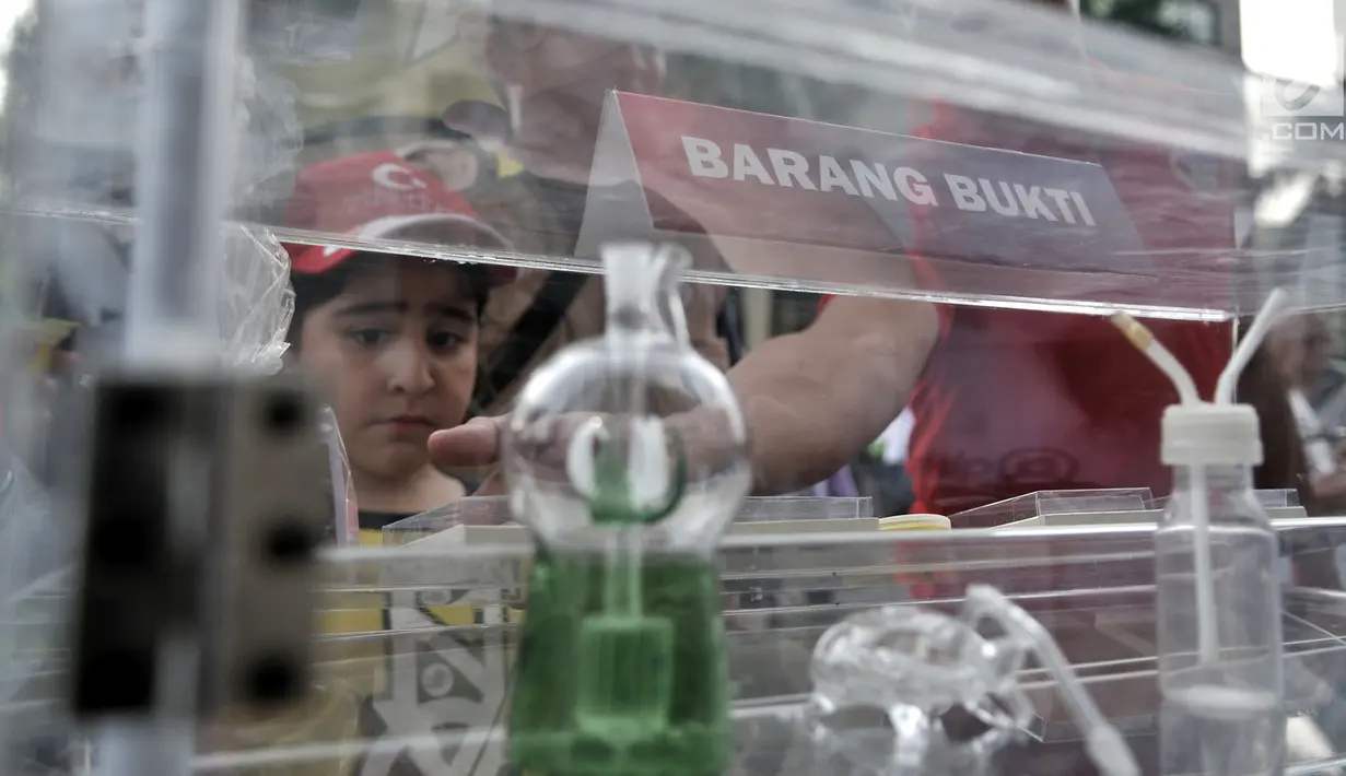 Pengunjung melihat berbagai jenis narkoba yang dipamerkan selama car free day (CFD) di Bundaran HI, Jakarta, Minggu (6/5). Pemeran ini dalam rangka memperkenalkan jenis-jenis narkoba sekaligus mensosialisasikan bahayanya. (Merdeka.com/Iqbal Nugroho)