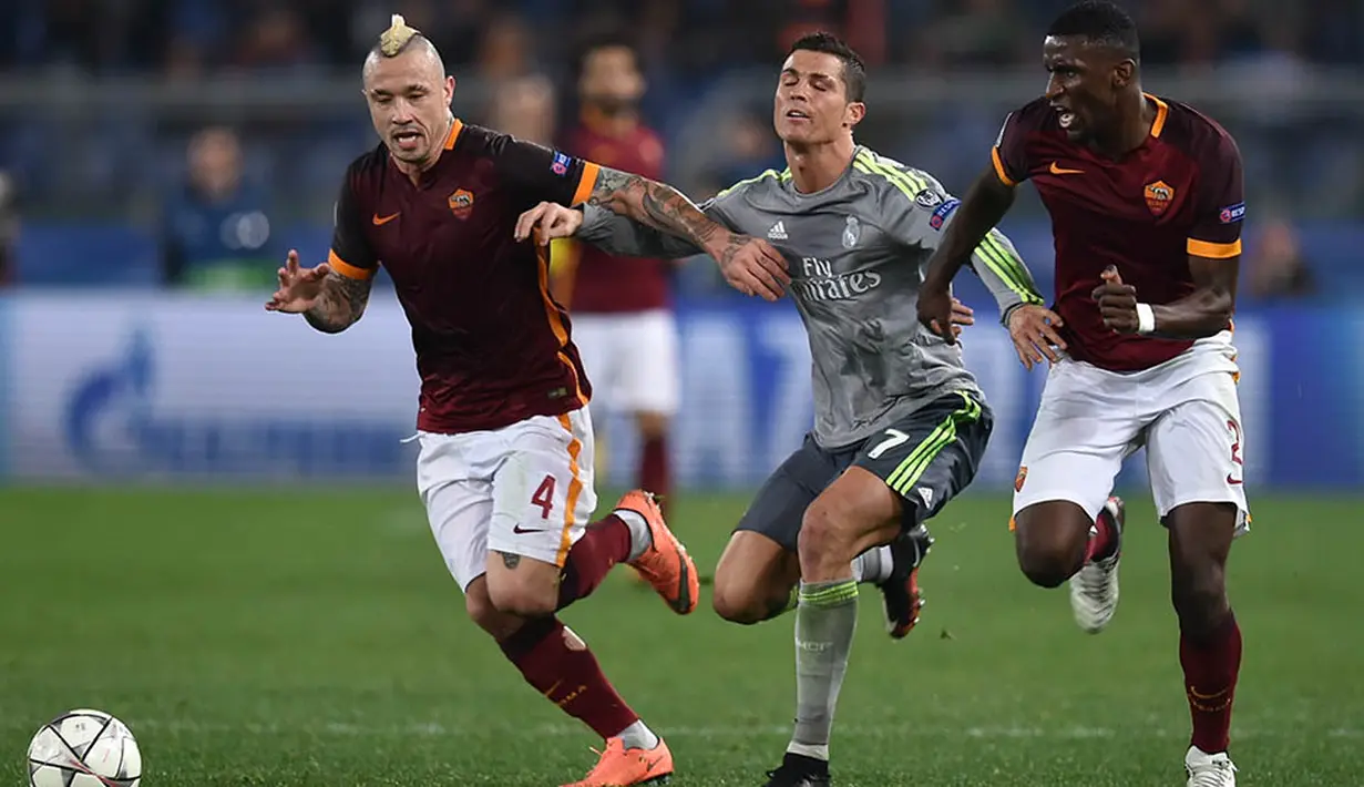 Pergerakan dari bintang Real Madrid, Cristiano Ronaldo, ditahan dua pemain Roma. Gol ke gawang Roma itu kian mengokohkan dirinya sebagai pencetak gol terbanyak Liga Champions sepanjang masa dengan torehan 89 gol. (AFP/Alberto Pizzoli)