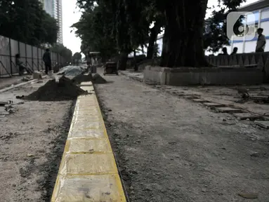 Pekerja Dinas SDA menyelesaikan proyek revitalisasi trotoar di Jalan RM Margono Djojohadikoesoemo, Jakarta, Kamis (16/1/2020). Trotoar di sisi selatan Kanal Banjir Barat itu akan dilengkapi taman dan deck view untuk melihat pemandangan Kali Ciliwung dan gedung perkantoran (merdeka.com/Iqbal Nugroho)