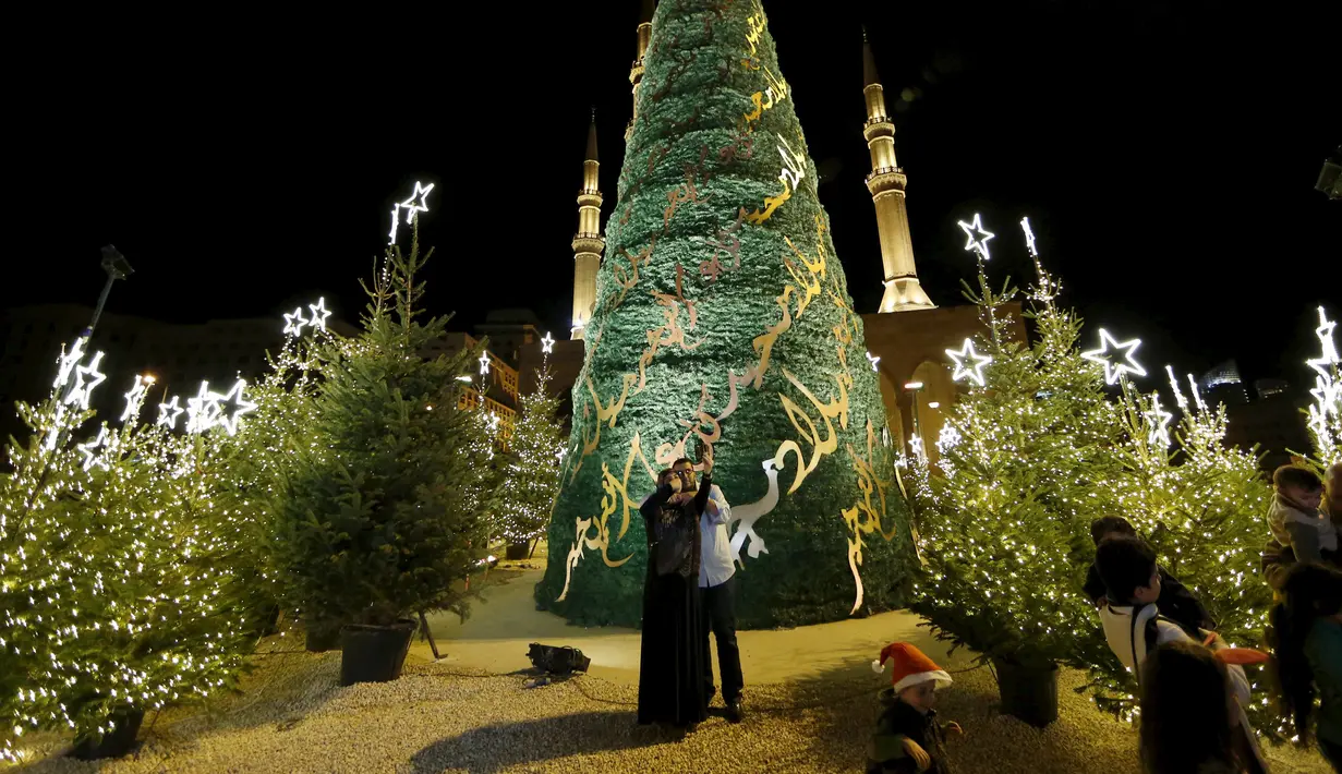 Warga berfoto dengan latar belakang pohon Natal yang dirancang oleh desainer Lebanon, Elie Saab di depan Masjid Al-Amin, di pusat kota Beirut, 12 Desember 2015. (REUTERS/Jamal Saidi)