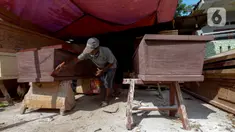 Herman pengrajin peti mati sedang mengecat pelitur untuk pembuatan peti mati di Pondok Kelapa, Jakarta Timur, Rabu (6/5/2020). Di tengah pandemi COVID-19 pembuatan peti mengalami kenaikan sekitar 15-30 peti di bandingkan hari biasanya. (merdeka.com/Imam Buhori)