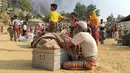 Pengungsi Rohingya menyelamatkan barang-barang mereka dan menyaksikan asap membubung menyusul kebakaran di kamp pengungsi Rohingya di Balukhali, Bangladesh selatan (22/3/2021). Kebakaran tersebut diperkirakan menghancurkan 900 tenda tempat ribuan pengungsi berlindung. (AP Photo/Shafiqur Rahman)