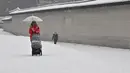 Seorang wanita mengendarai kursi dorong di sepanjang jalan yang tertutup salju di pusat kota Seoul (19/1/2022). Peringatan salju tebal telah dikeluarkan di seluruh kota pada pukul 9 pagi. (AFP/Jung Yeon-je)