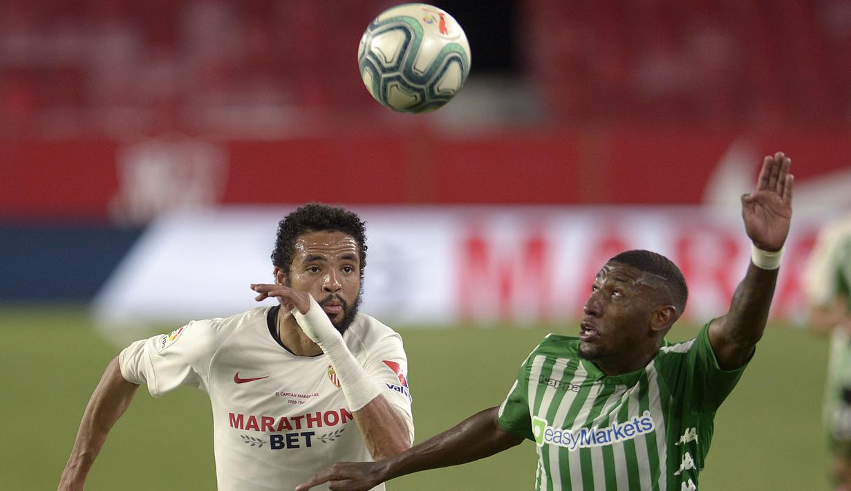 Penyerang Sevilla, Youssef En-Nesyri, berebut bola dengan bek Real Betis, Emerson Aparecido, pada laga lanjutan La Liga di Estadio Ramon Sanchez Pizjuan, Jumat (12/6/2020) dini hari WIB. Sevilla menang 2-0 atas Real Betis. (AFP/Cristina Quicler)