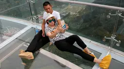 Pasangan berfoto selfie di atas platform kaca di Jurang Shilin, Beijing, Cina, (27/5). Para pengunjung diwajibkan mengenakan alas kaki khusus untuk mencegah kerusakan kaca saat berwisata ketempat ini. (REUTERS/Kim Kyung-Hoon)