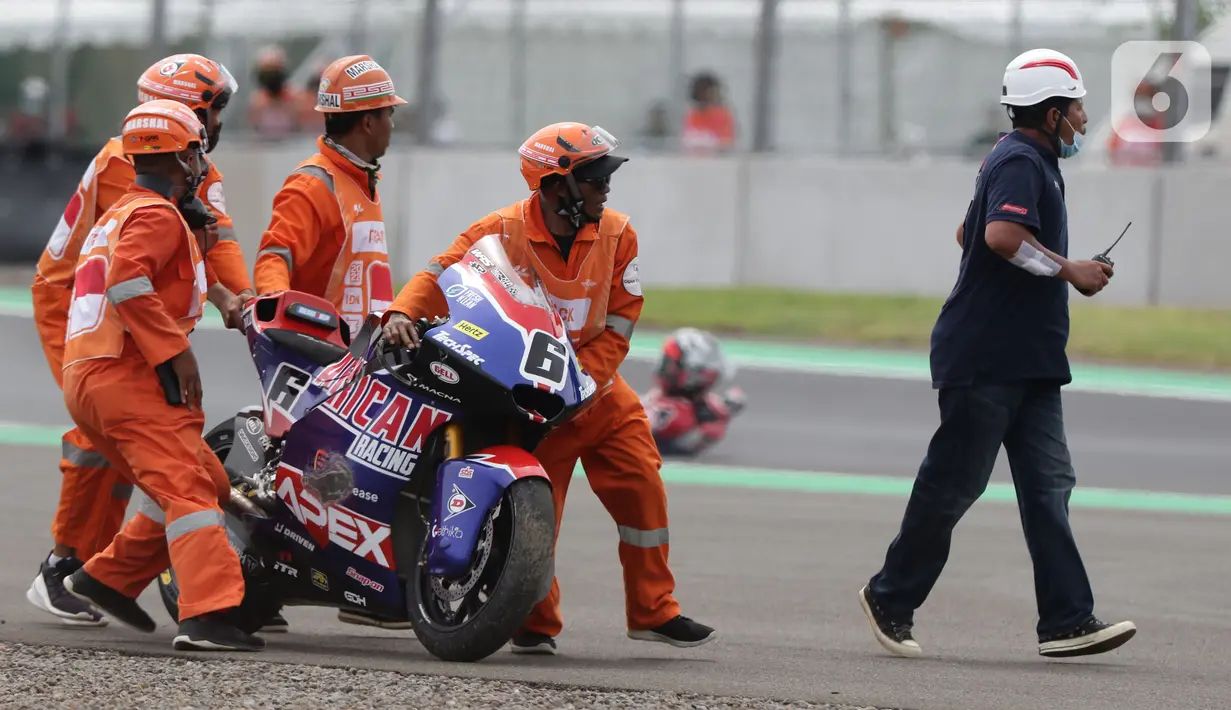 Marshal mendorong motor pembalap Cameroon Beaubier saat kualifikasi Moto2 di Pertamina Mandalika International Street Sirkuit, Lombok, NTB, Sabtu (19/3/2022). Trackside Marshal bertanggungjawab memastikan lintasan bebas dari hal berpotensi membahayakan pembalap. (Liputan6.com/Helmi Fithriansyah)