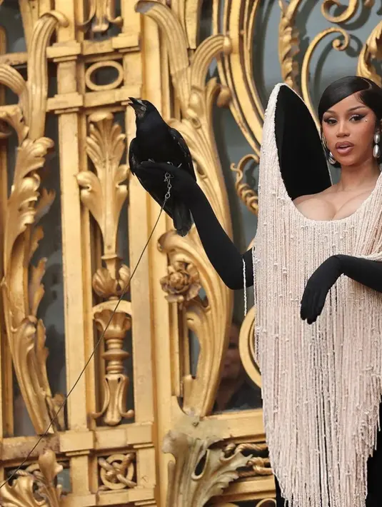 Tak hanya gaunnya yang mencuri perhatian, Cardi B juga menambah unsur teatrikal dengan membawa burung gagak hidup di tangan kirinya, lengkap dengan sarung tangan opera hitam yang makin menguatkan kesan misterius dan megah. Tampilan ini langsung jadi pusat sorotan fotografer dan tamu undangan yang memadati venue. [@cardifansbr].